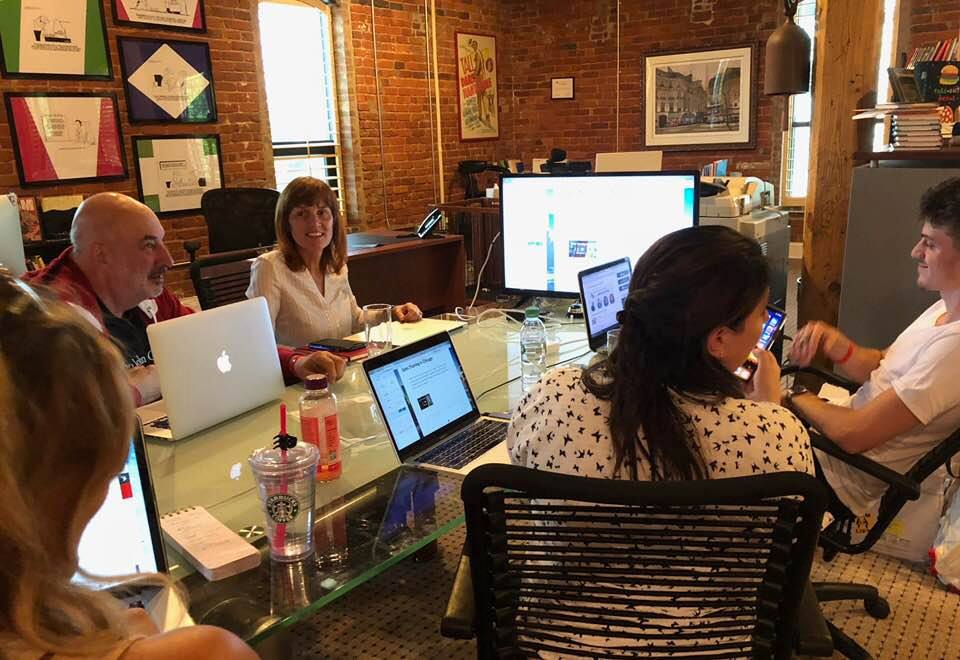 6 people seated at table with laptops