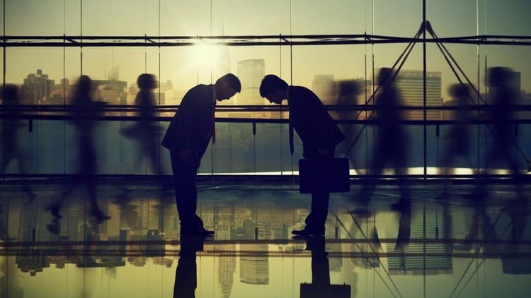 Two people in suits bowing in respect