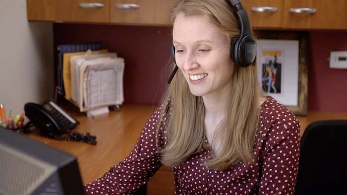 Woman smiling at work with her headset on her desktop computer