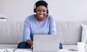Woman sitting on couch, virtual training on laptop