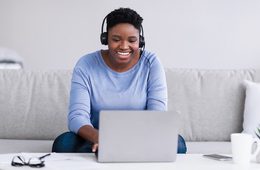 woman sitting on couch, virtual training on laptop