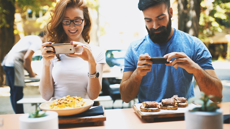 two friends taking photos of food